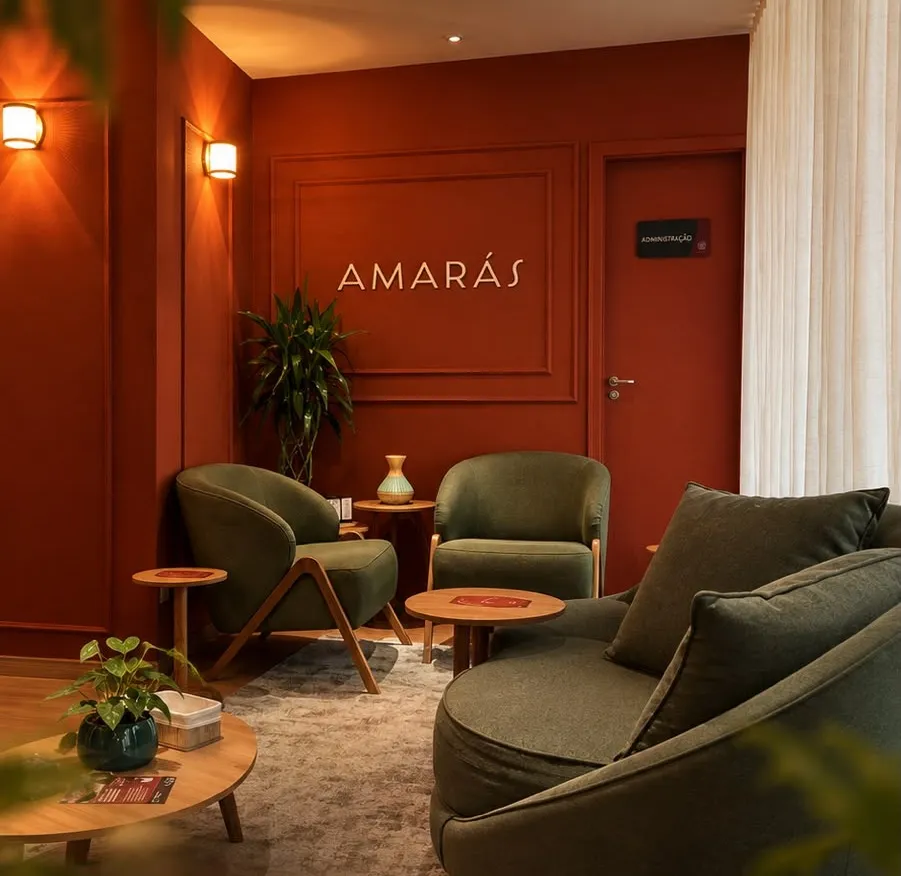 Lounge terracota com poltronas verdes, sofá e o letreiro Amarás